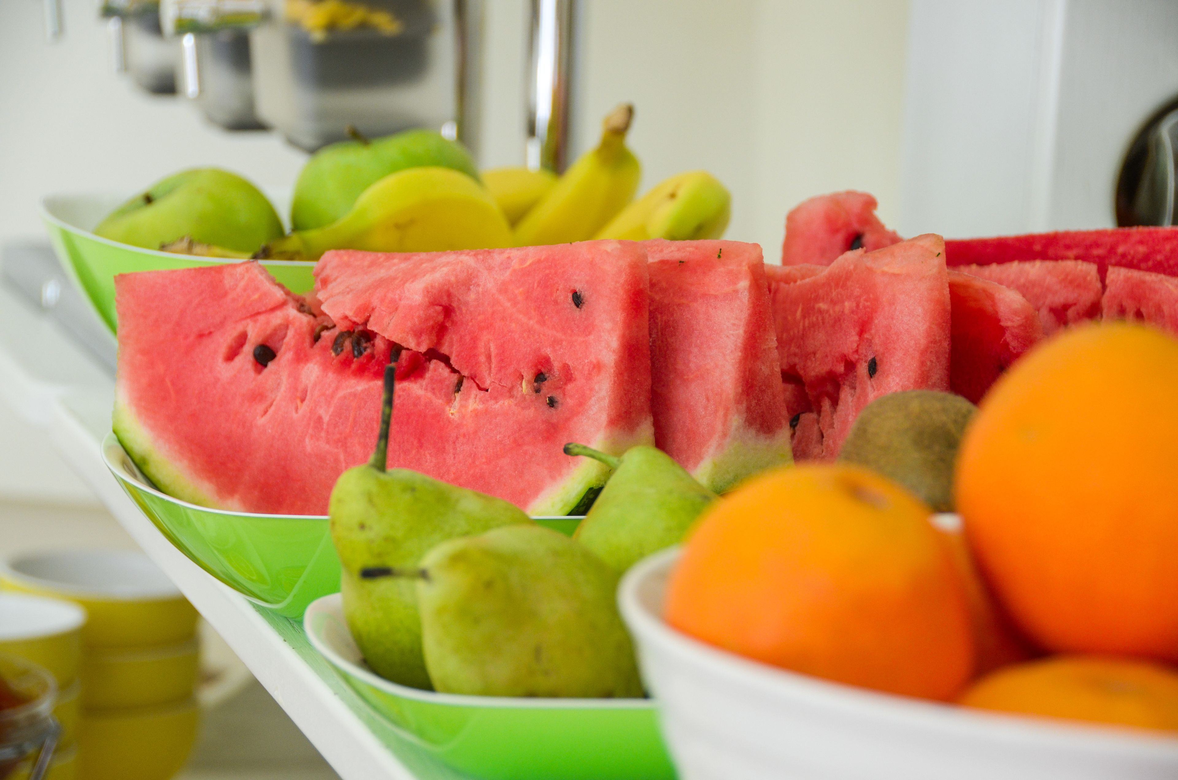 A fruit bowl containing watermelon, pears, bananas, and oranges.