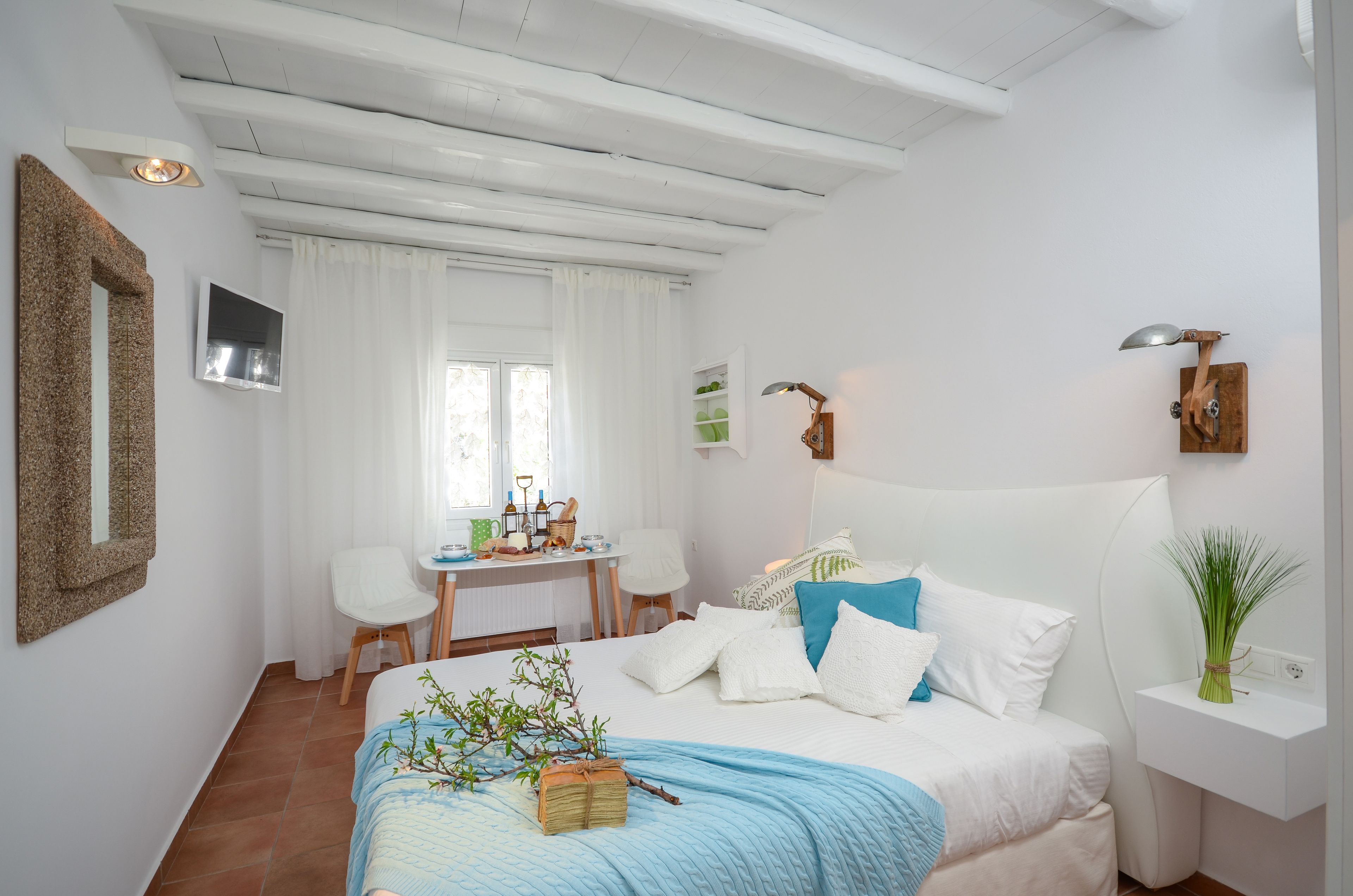 Une chambre à coucher comprenant un lit, une table de chevet, un bureau, une chaise et un téléviseur fixé au mur.