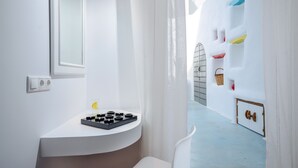 A modern bathroom with a white sink, a mirror, and a window. There is a white door leading to another room. - Adriani Hotel (Naxos)