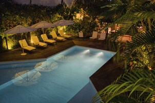 Una piscina al aire libre, sombrillas, sillones reclinables de piscina