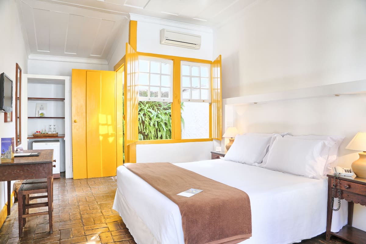 A hotel room with a bed, bedside table, and a desk with a chair.
