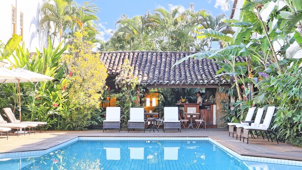 Une piscine dotée de chaises longues et d’un espace bar, le tout entouré de plantes tropicales.