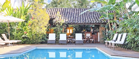 Una piscina al aire libre, sombrillas, sillones reclinables de piscina