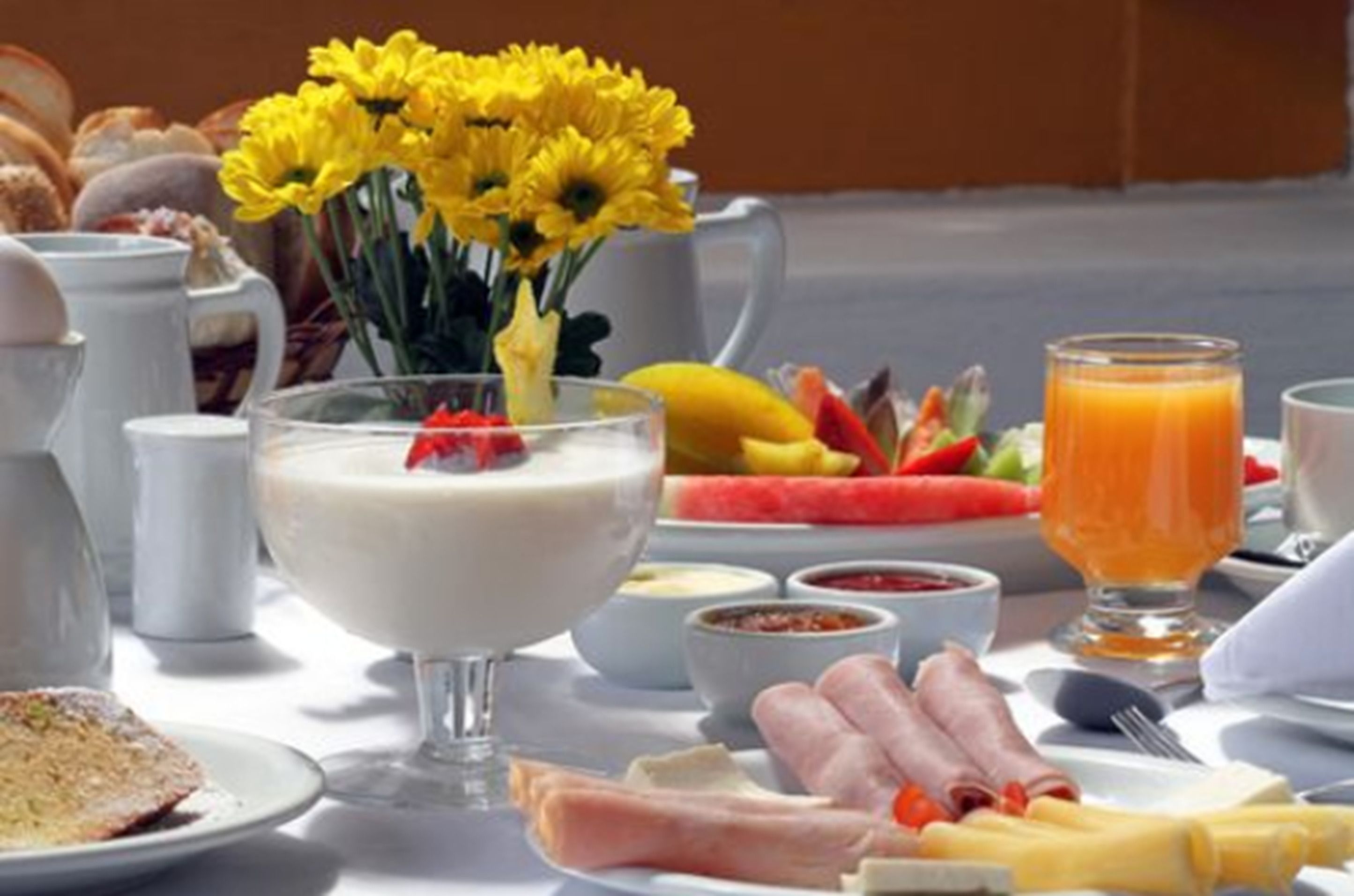 A breakfast setting with a variety of food items including eggs, fruits, and a glass of orange juice.
