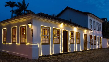 Un edificio blanco con varias ventanas y puertas, iluminado por luces cálidas.