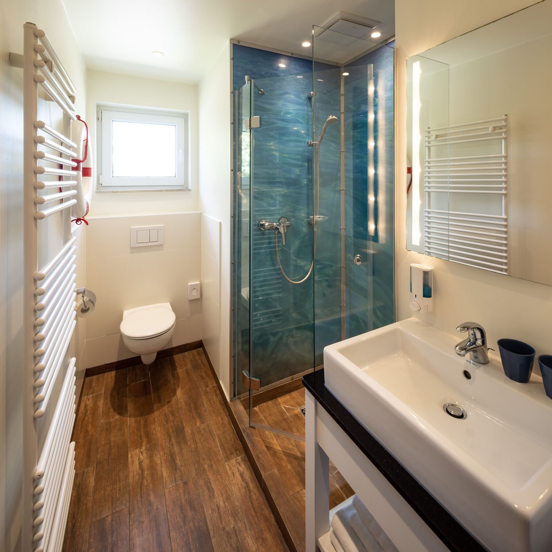 Un baño moderno con ducha de vidrio, inodoro blanco y lavamanos con espejo.
