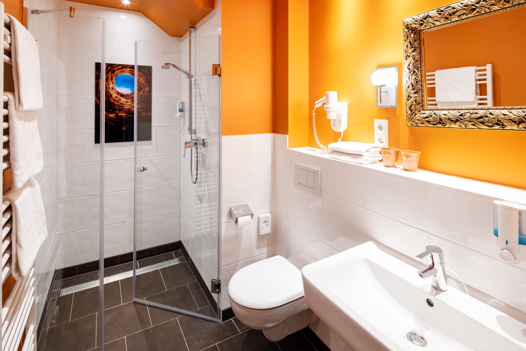 A modern bathroom with a glass shower enclosure, a white toilet, and a sink with a mirror.