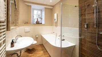A modern bathroom with a freestanding bathtub, a glass-enclosed shower, and a large mirror.