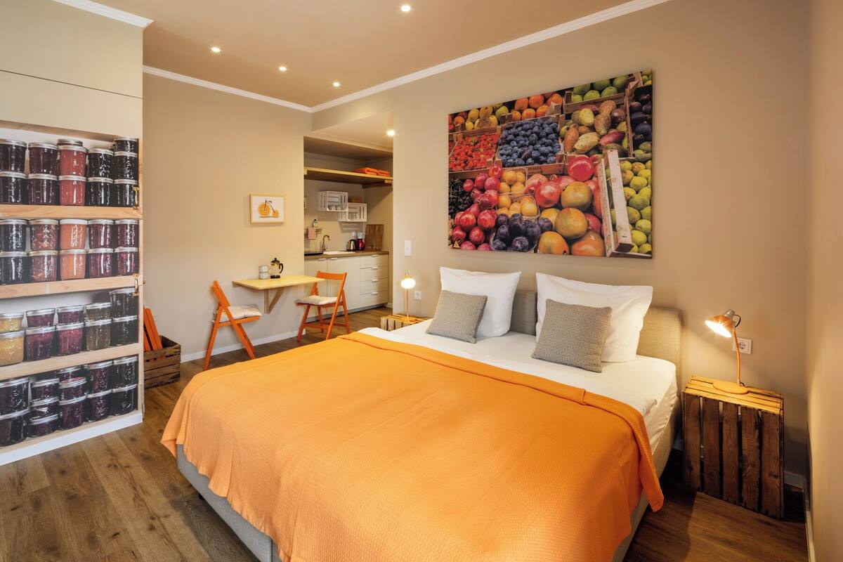 Un dormitorio con una cama grande, una mesita de noche de madera, un escritorio con silla y un frutero montado en la pared.
