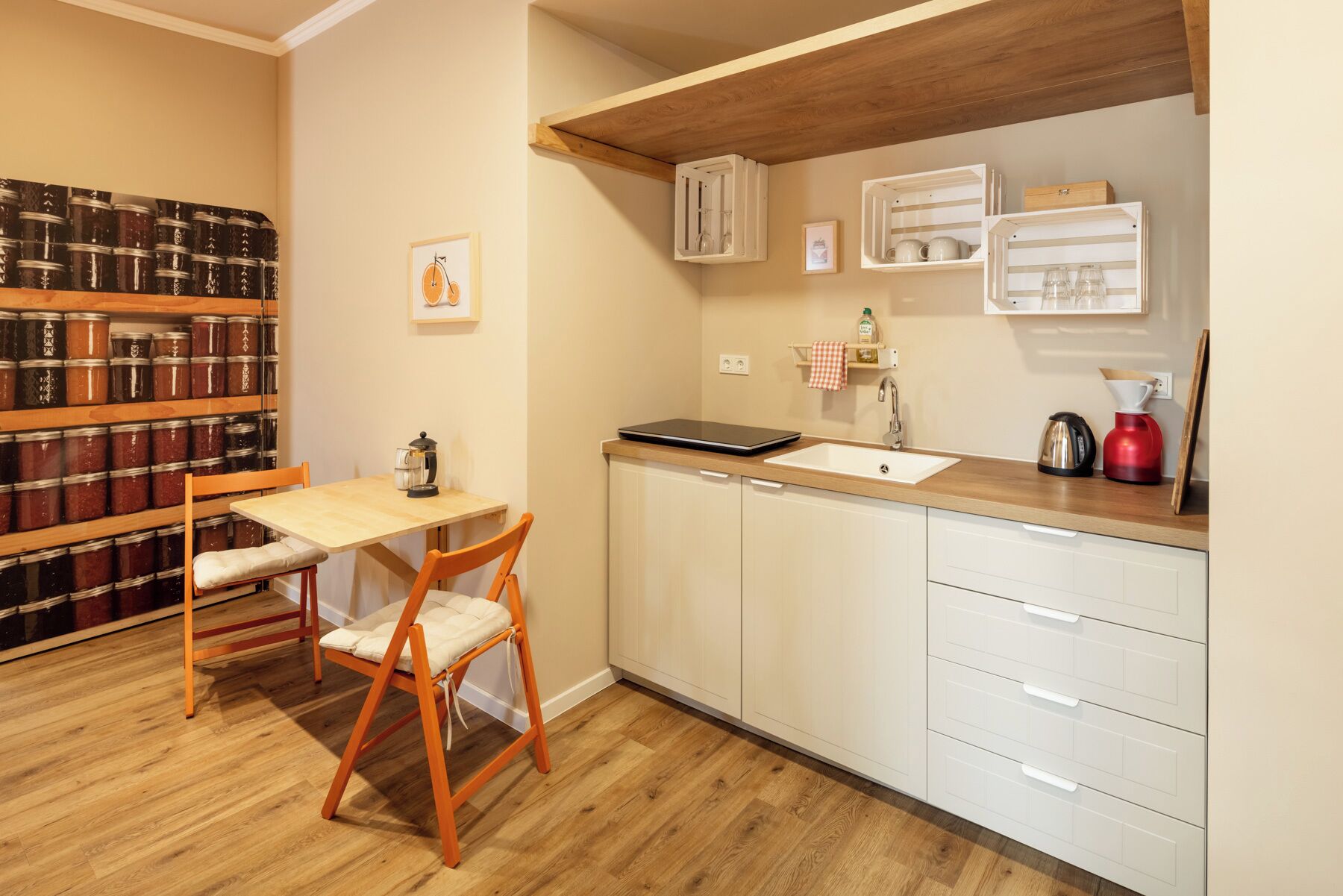 A compact kitchen with a wooden table and chairs, a sink, and a coffee maker.