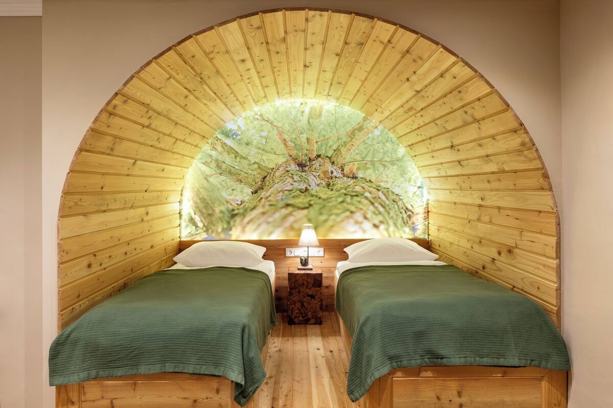 Una habitación acogedora con dos camas, techo de madera y una lámpara de pared.