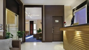 Zona d'entrada d'hotel amb taulell de recepció, un sofà i un passadís que condueix a una habitació.