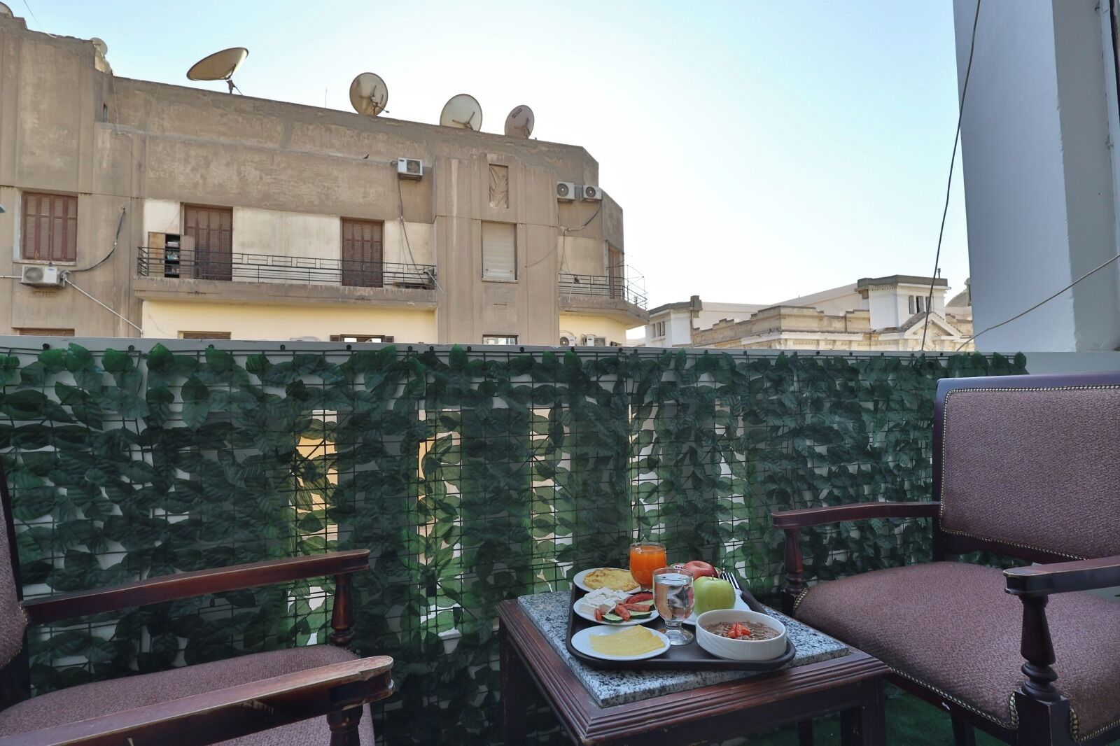 A balcony with a table set for breakfast, a chair, and a decorative plant wall.