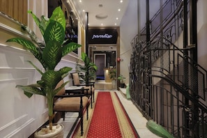 A hotel corridor with a red carpet, potted plants, and a staircase with metal railings. - Cairo Paradise Hotel (Cairo)