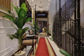 A hallway with a red carpet leading to a door labeled 'paradise.' There are potted plants on the left and a black wrought iron railing on the right. - Cairo Paradise Hotel (Cairo)