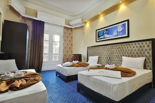 Een hotelkamer met twee bedden, een groot raam, een airconditioner en een lijst met een afbeelding aan de muur.