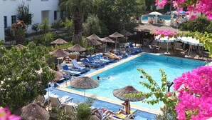 A swimming pool with lounge chairs and umbrellas, surrounded by greenery and buildings. - Bodrum Park Hotel (Bodrum)