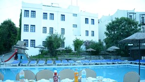 A poolside dining area with tables set for meals, lounge chairs, and umbrellas. - Bodrum Park Hotel (Bodrum)