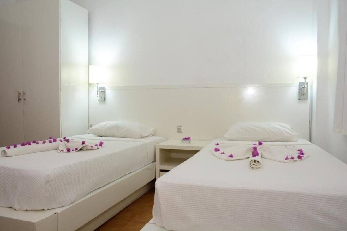 A hotel room with two single beds, a nightstand, and a wardrobe.