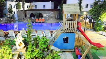 Relax by the pool surrounded by a play structure, seating area, and lounge with umbrellas.