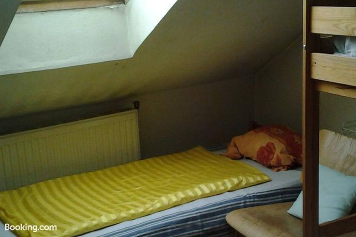 A small, single-bed room with a sloped ceiling and a wooden bunk bed on the right.