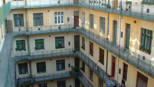 Un edificio residenziale a più piani con balconi, persiane e piante da esterno.
