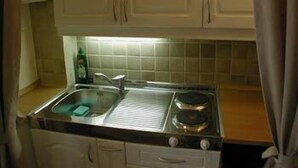 Una cucina con lavello, fornelli e pensili.