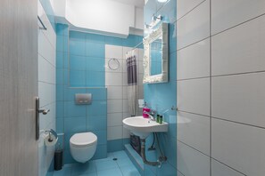 A bathroom with a toilet, sink, and shower area. - Ouzas Luxury Hotel (Katerini)