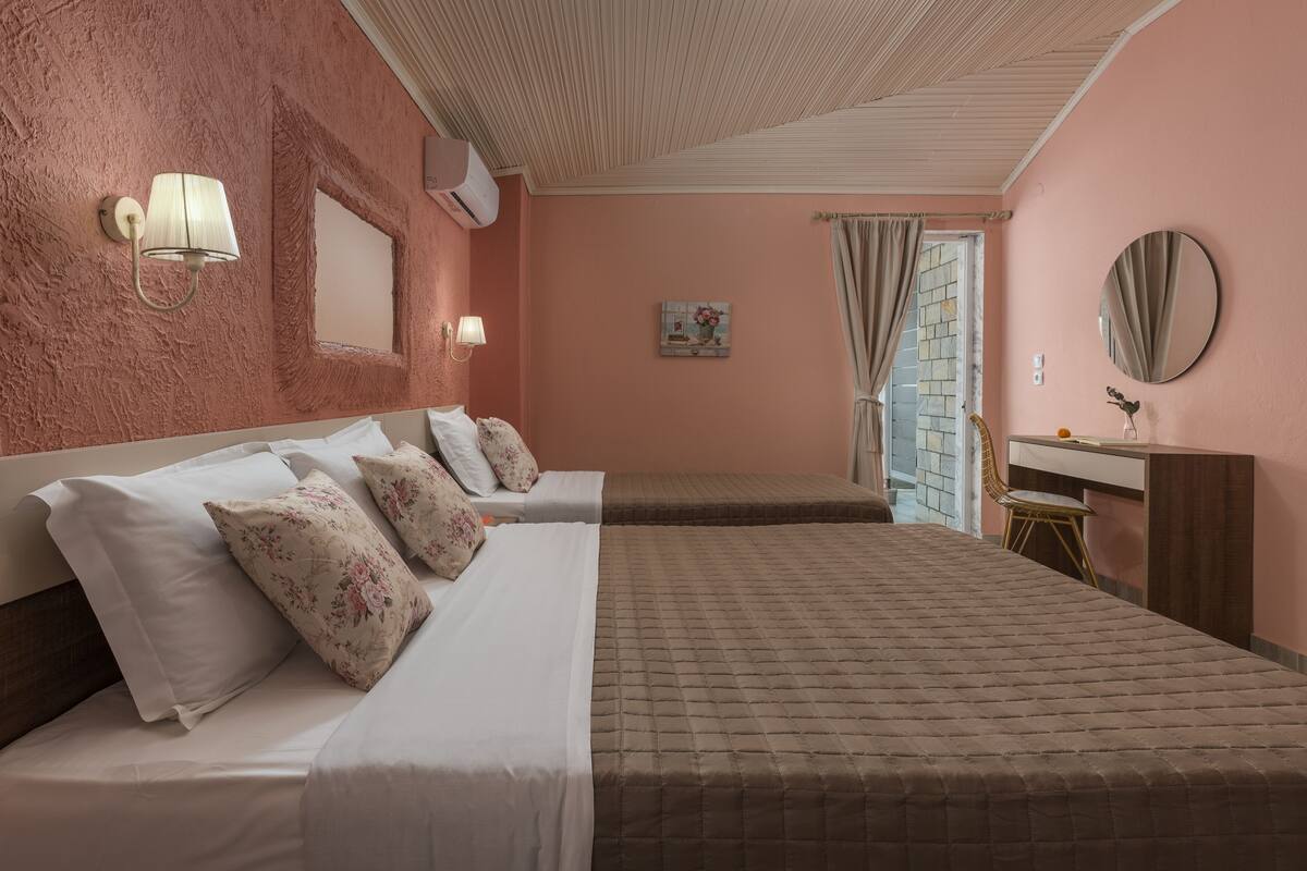 A bedroom with two beds, a desk, a chair, a mirror, and a window with curtains.