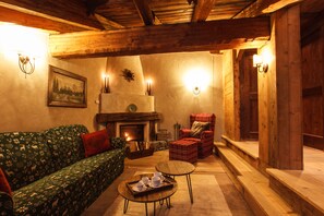 Un salón acogedor con chimenea, un sofá, un sillón y una mesita con tazas y platillos.
