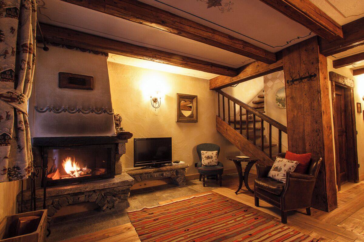 Una sala de estar acogedora con chimenea de piedra, televisor y un espacio de descanso cómodo con sillón y sofá.