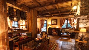 Een rustiek interieur met houten balken, een stenen open haard en traditionele decoratie.