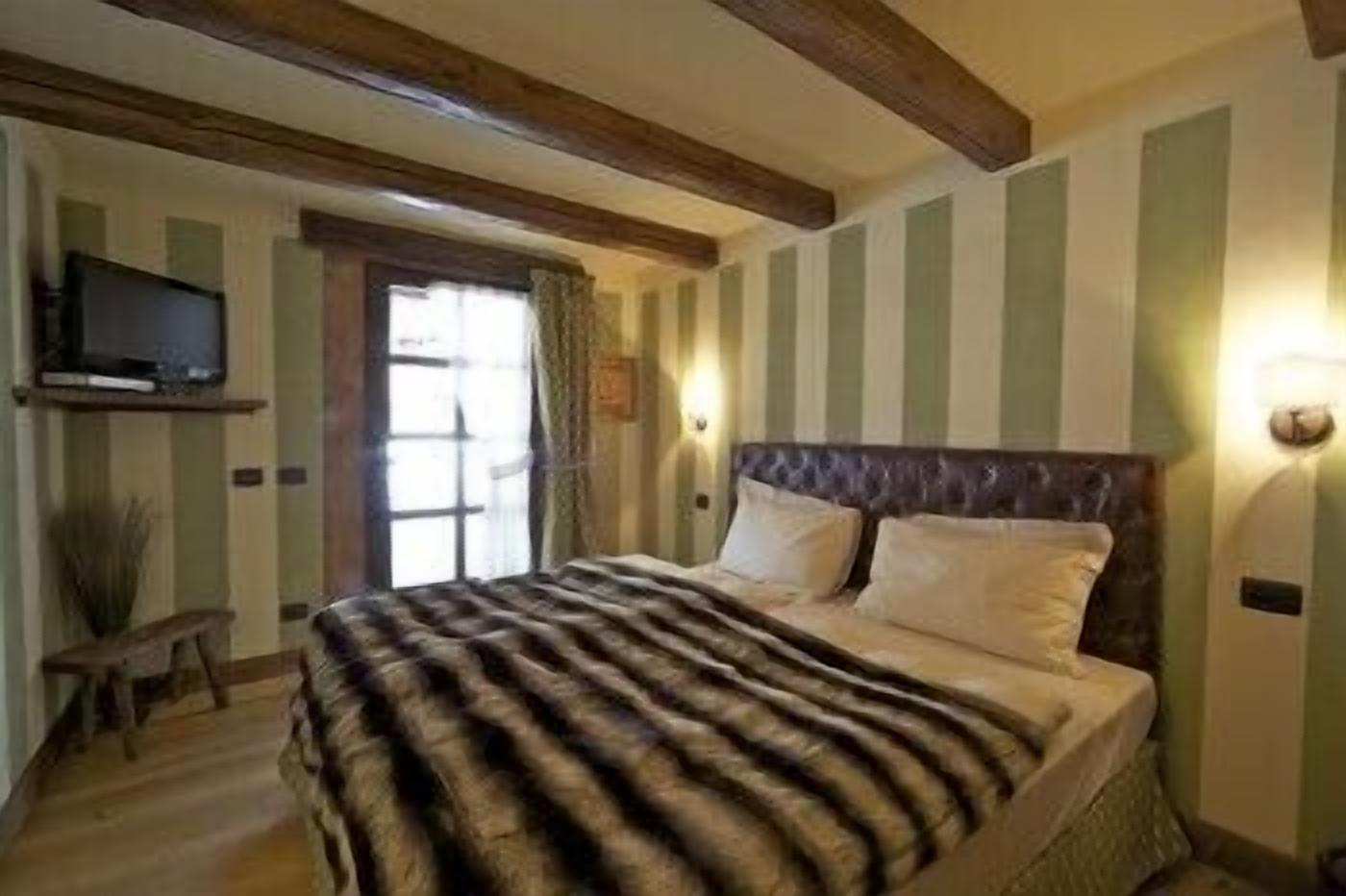 Un dormitorio con cama, televisión en la pared y ventana con cortinas.