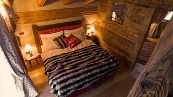 A cozy wooden room with a bed, two bedside tables, and a window.