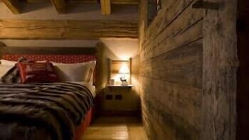 Una stanza piccola con pavimento in legno, un letto, un comodino e una lampada.