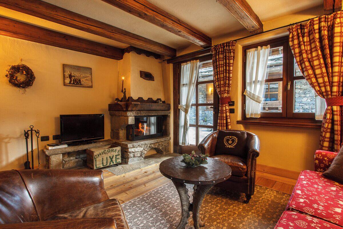 Una sala de estar acogedora con chimenea, muebles de cuero y un revestimiento de piedra alrededor de la chimenea.