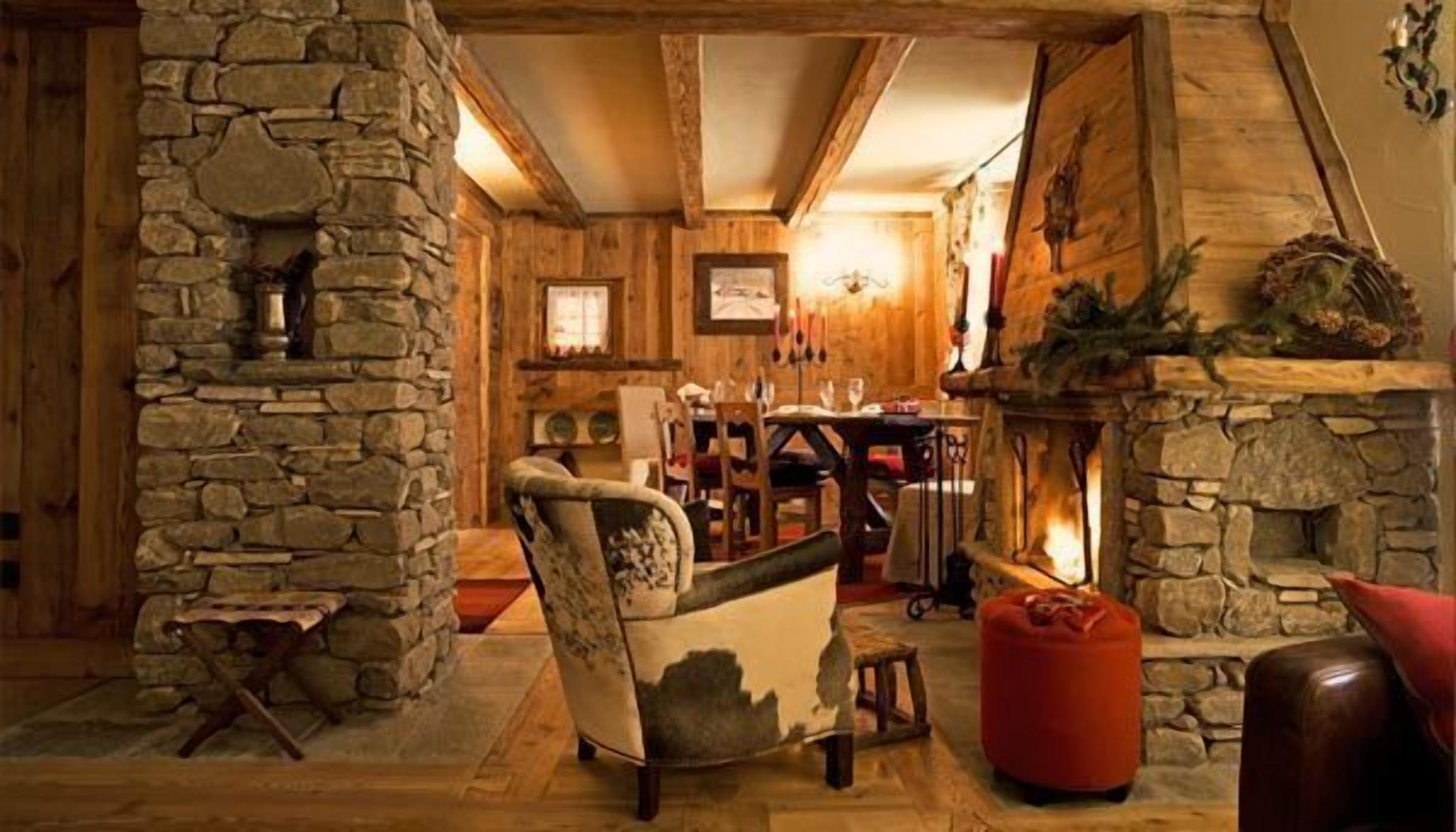A rustic interior with stone walls, a fireplace, wooden furniture, and a cozy seating area.