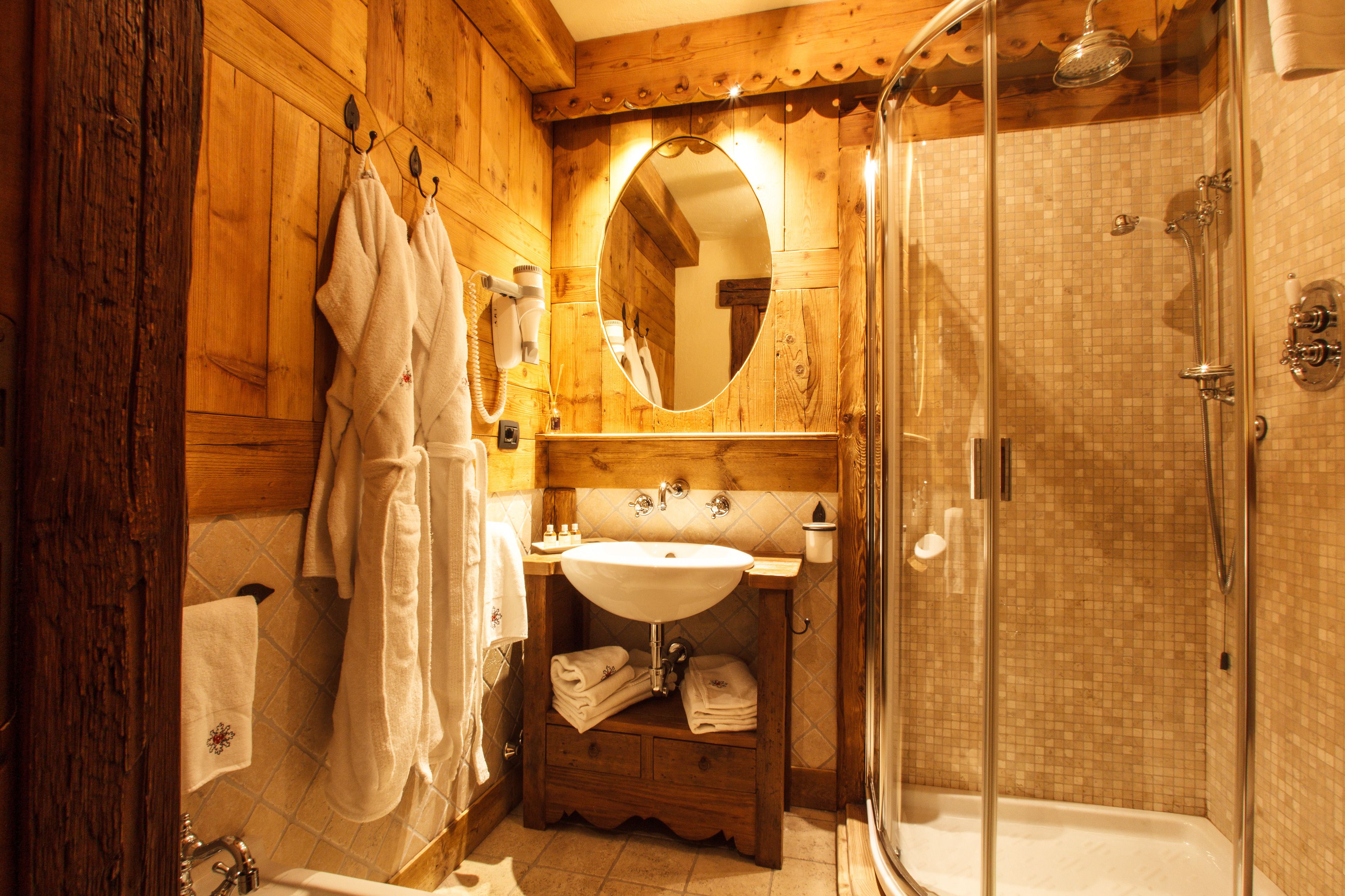 A wooden bathroom with a glass-enclosed shower, a sink, and a mirror.
