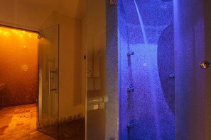 Un área de ducha con mampara de vidrio, suelo de azulejos y ducha visible.