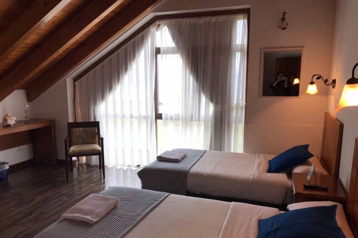 A bedroom with two beds, a desk, and a chair.