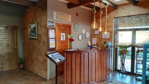 A reception area with a wooden counter, a wall clock, a sign indicating WiFi availability, and a bulletin board with various notices. - Hotel Rustico Prado Da Viña (Fisterra)