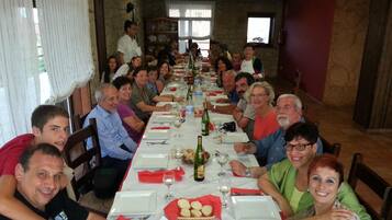 Una llarga taula de dinar preparada per a les menjades, amb diverses persones assegudes al voltant.