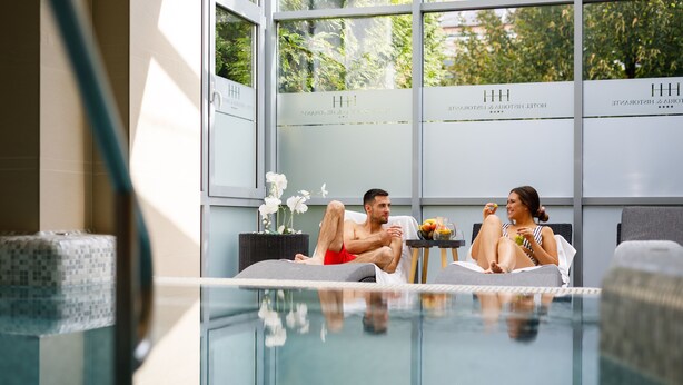 Una habitación de hotel moderna con una piscina envuelta en cristal, vistas a zonas verdes y un diseño interior minimalista.