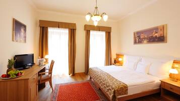 A hotel room with a bed, desk, television, and artwork on the walls.