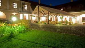Un patio con zona de estar cubierta, sendero de piedra y vegetación.