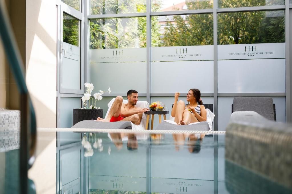 A modern hotel room with a glass pool, a sofa, and a dining table with flowers.