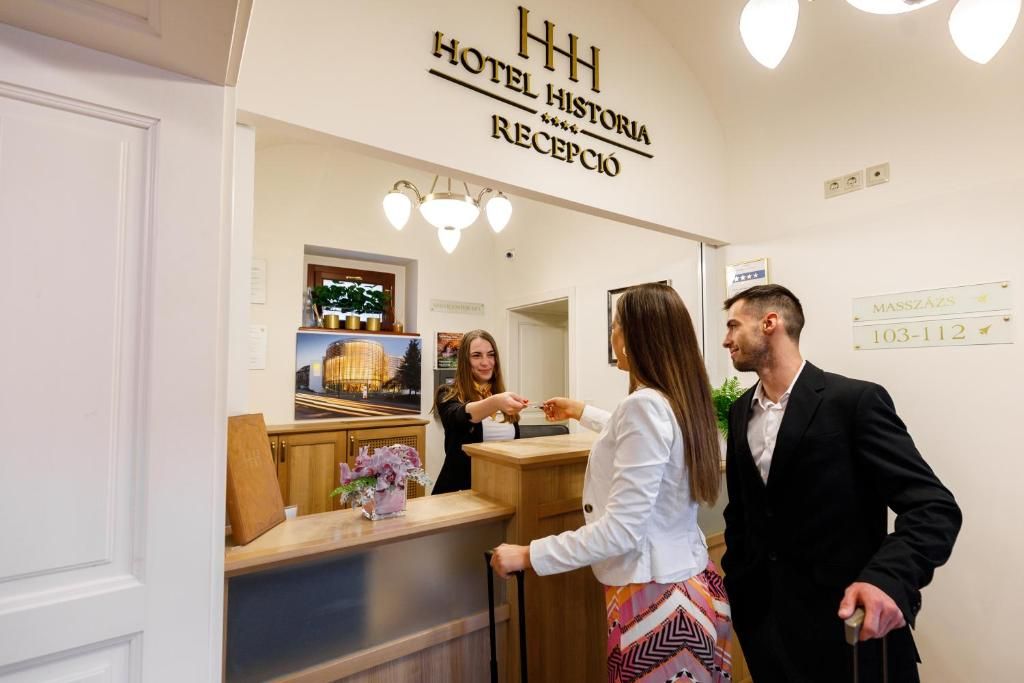 A hotel reception area with a reception desk, a mirror, and a sign indicating the hotel name and reception.