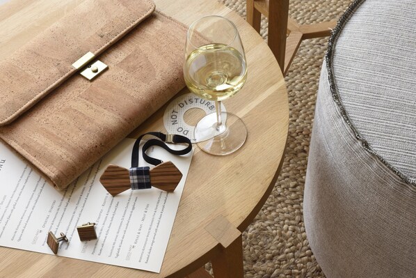 A wooden table with a glass of white wine, a brown leather bag, and wooden cufflinks on a menu.