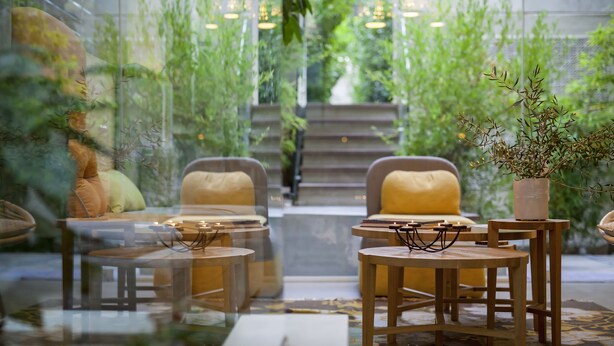 A modern interior with a glass partition, wooden furniture, and a view of a staircase leading to a green outdoor area. - COCO-MAT Hotel Nafsika (Kifisia)