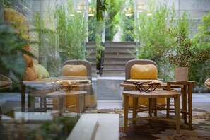 A modern interior with a glass partition, wooden furniture, and a view of a staircase leading to a green outdoor area. - COCO-MAT Hotel Nafsika (Kifisia)